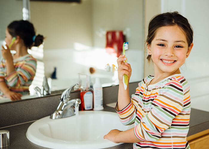 A young girl holding her toothbrush up