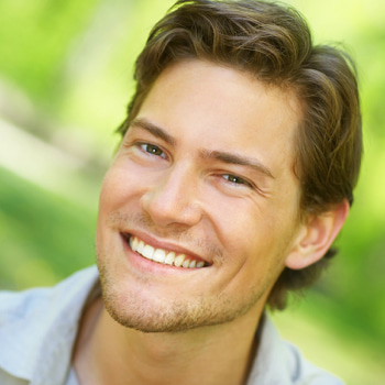 A brunette man smiling outdoors
