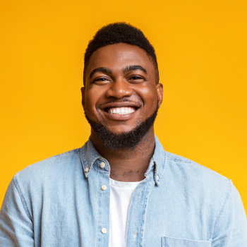 A young man smiling in a yellow background