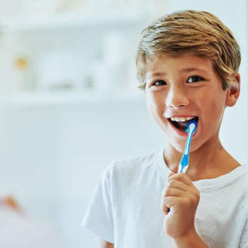 A young boy brushing his teeth in front of the mirror